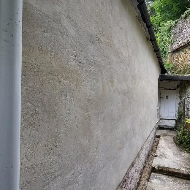 Fresh lime render on an exterior wall beside a stone garden wall
