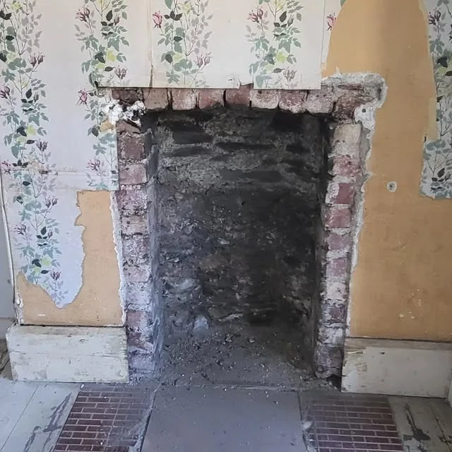 Exposed stone and brick fireplace during preparation for traditional repair